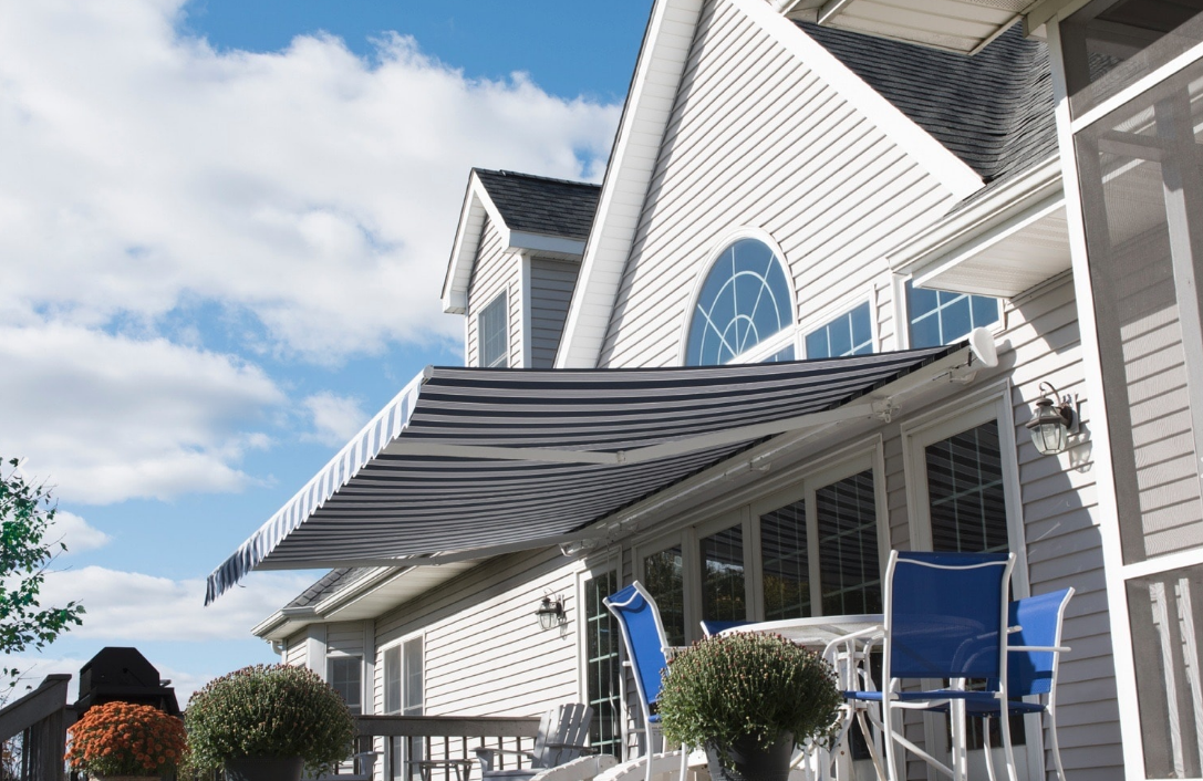 A white house with blue chairs and a black and white awning